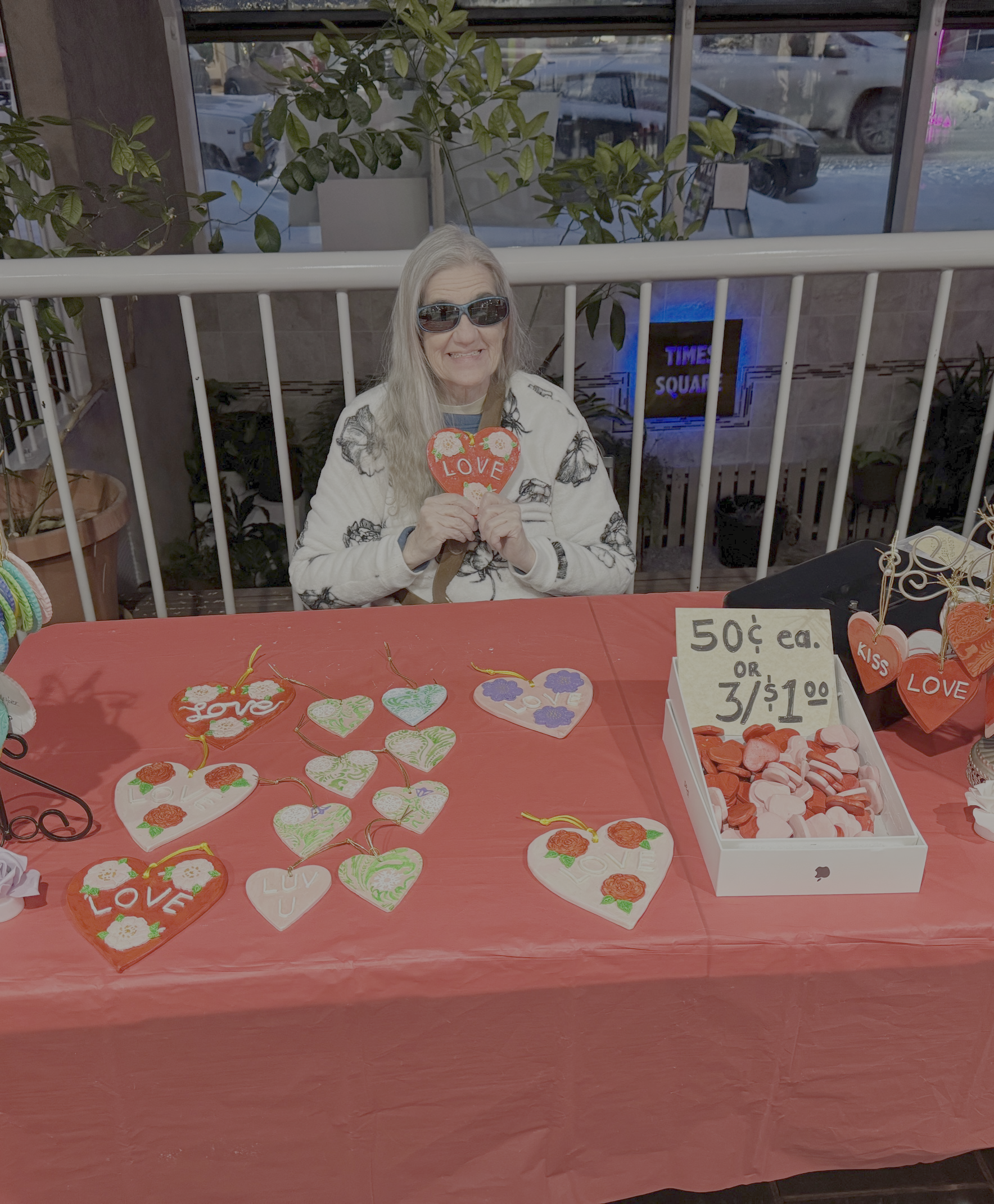 Kristi holding a clay heart up with the word love on it.