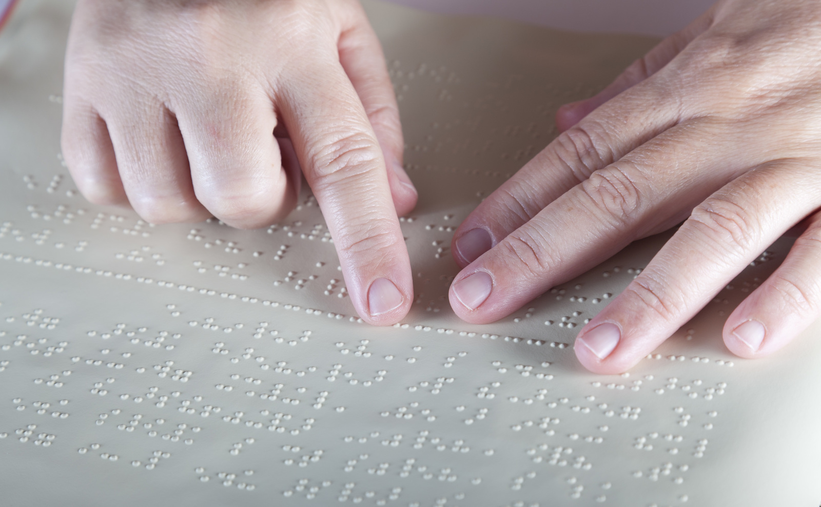 A person placing their hands on embossed paper,  learning to read braille.