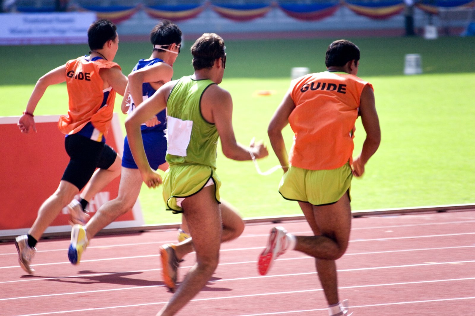 A sited guide running with a blind runner on a track.