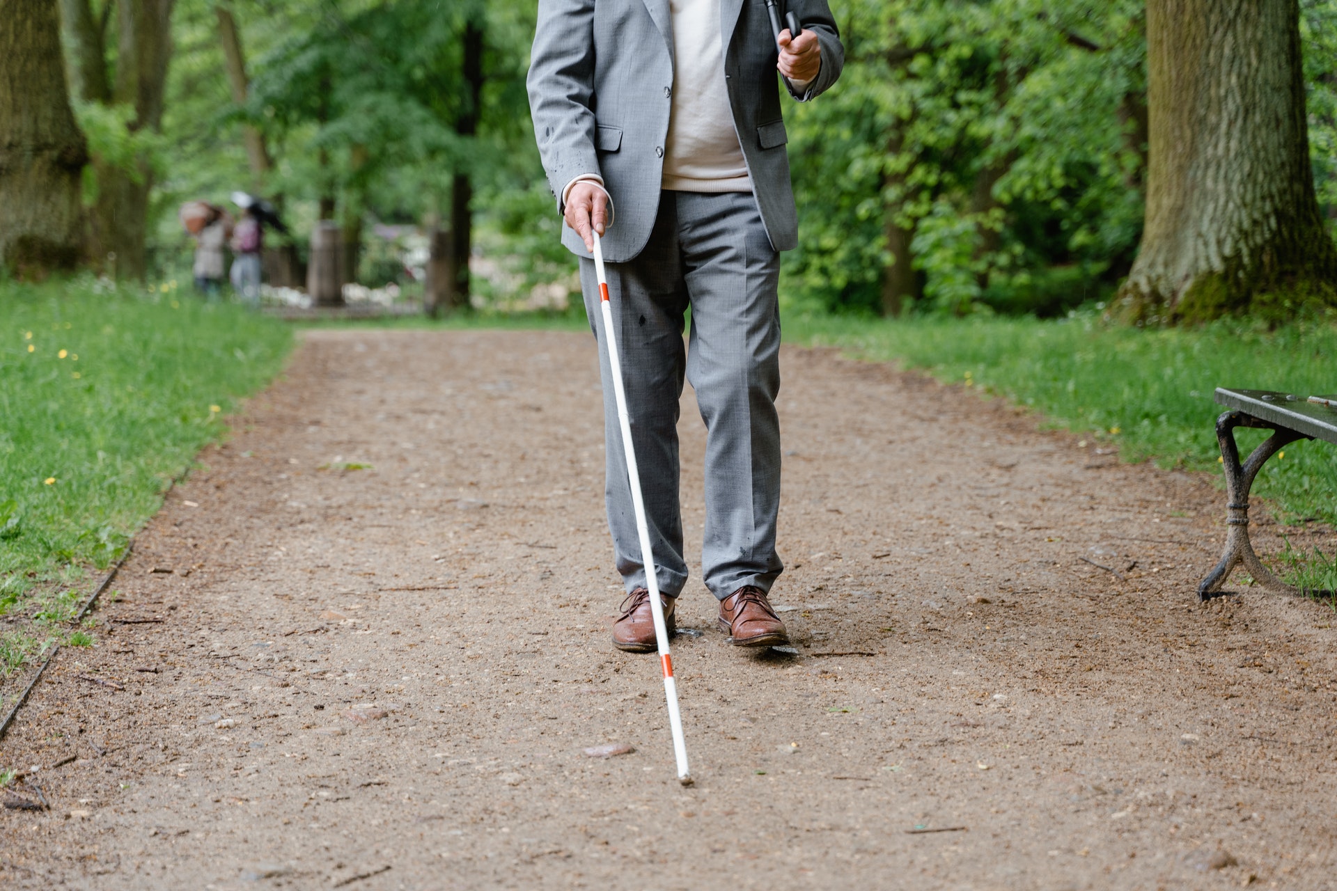 A man walking with a white mobility cane.